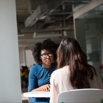 two female students sitting at a table and talking