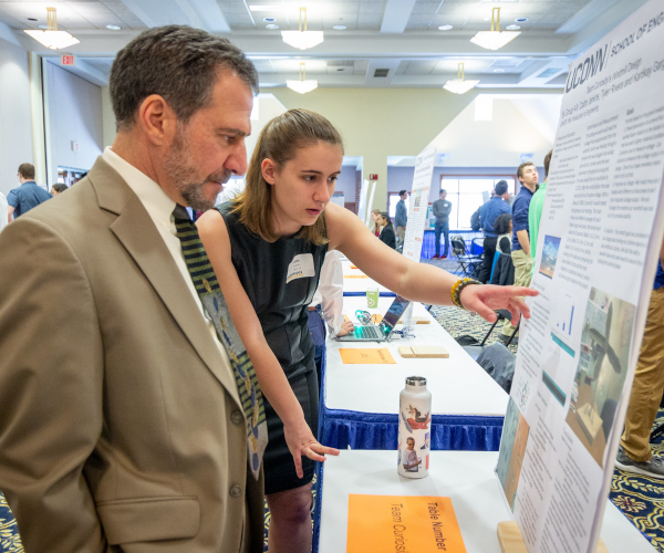 michaeo accorsi with a female student observing her poster board of her research