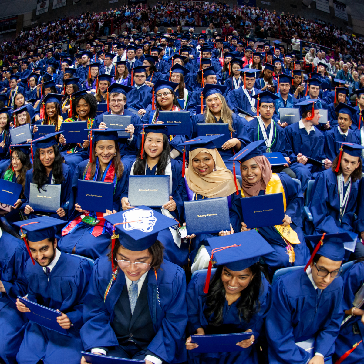 may 2024 commencement of graduates sitting in gampel with diplomas